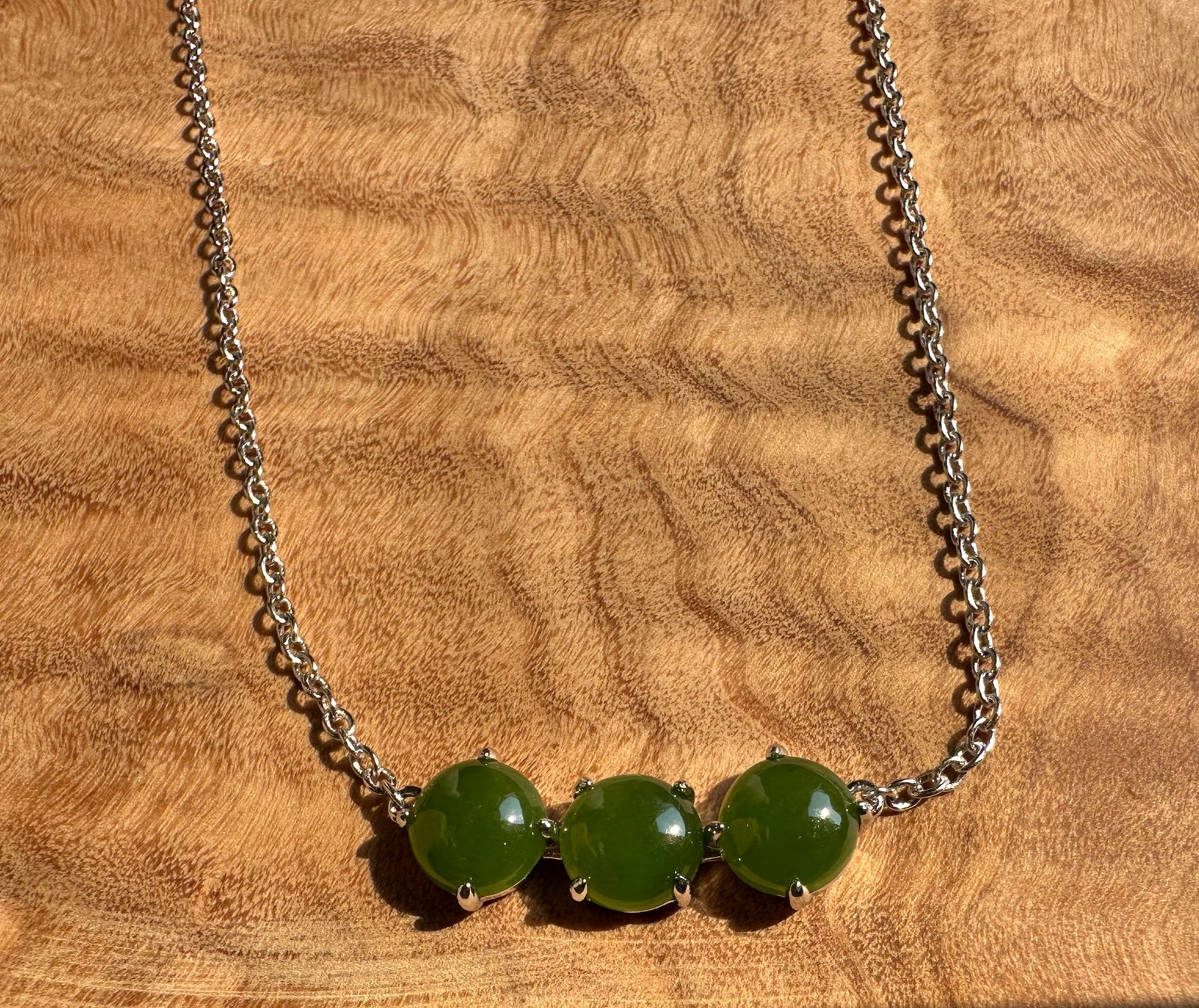 Three green jade beads set in silver bezels along a silver chain necklace.