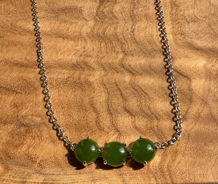 Three green jade beads set in silver bezels along a silver chain necklace.