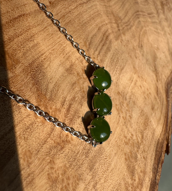 Canadian Jade and Silver three bead necklace displayed on a wooden surface with three green jade stones along a silver chain