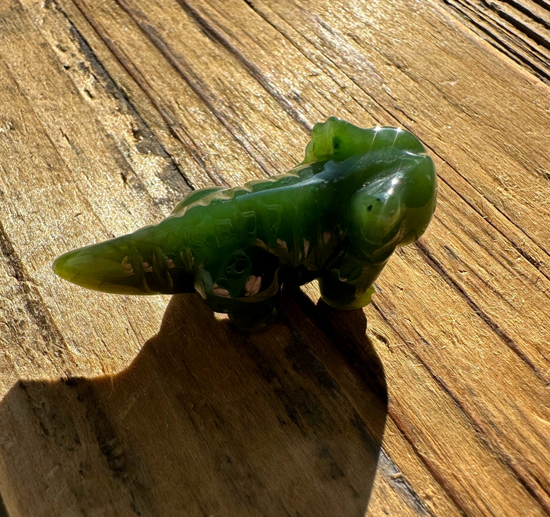 Side view of green jade axolotl 1.5 inch carving on sunlit wood.