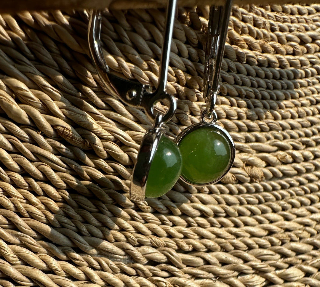 Close-up of jade round leverback earrings showing green stones set in silver bezels.