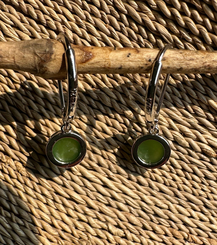 Pair of jade round 6mm leverback earrings with green stones in silver settings on a woven background.