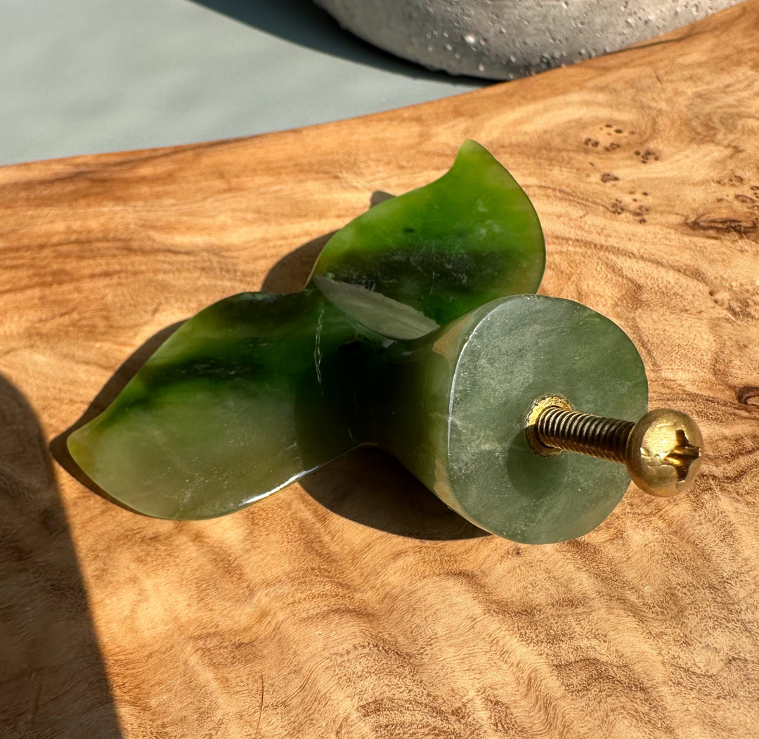 Green jade whale tail drawer pull seen from the side with a round brass screw base