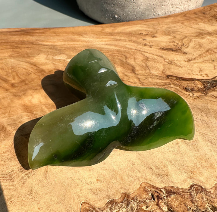 Top view of green jade whale tail drawer pull on a wooden surface