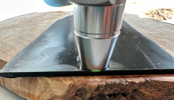 Polishing head pressed onto a black Wyoming Jade slab on a wooden work surface.