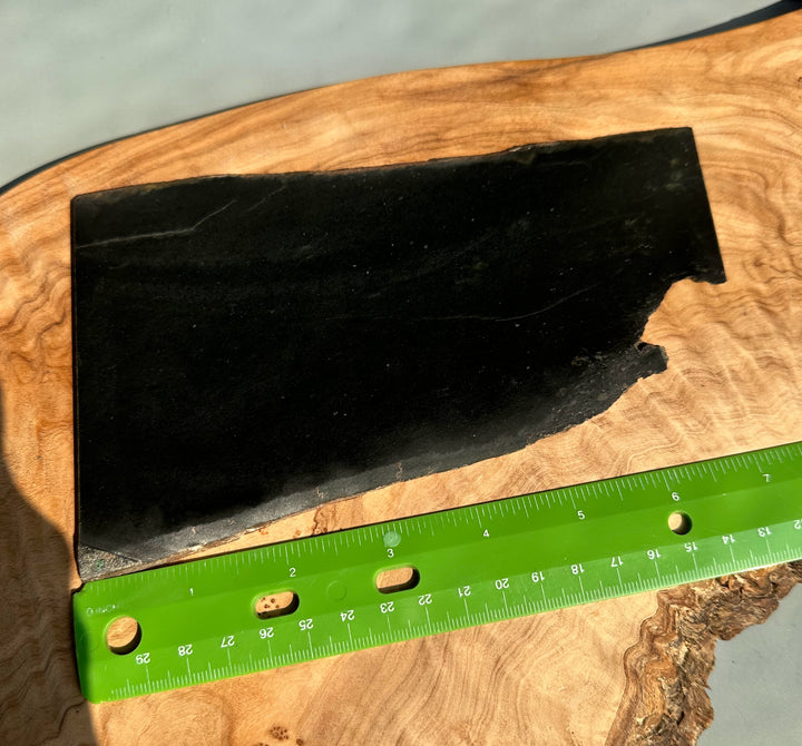 Wyoming Jade Slab 205 grams, black and smooth on a wooden surface with a green ruler for scale