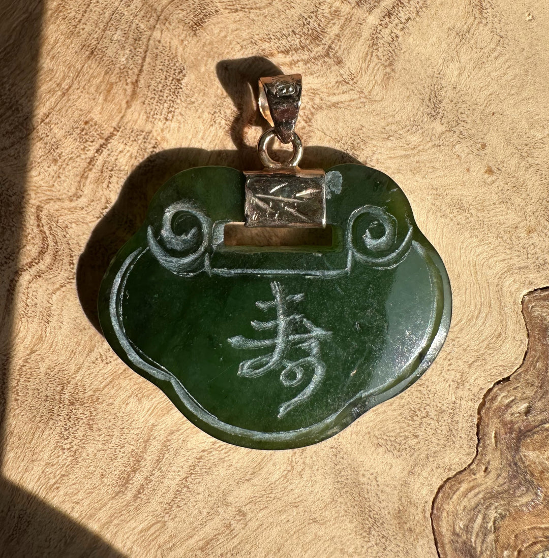 Vintage green jade flower pendant with swirling carved motifs and a metal bail