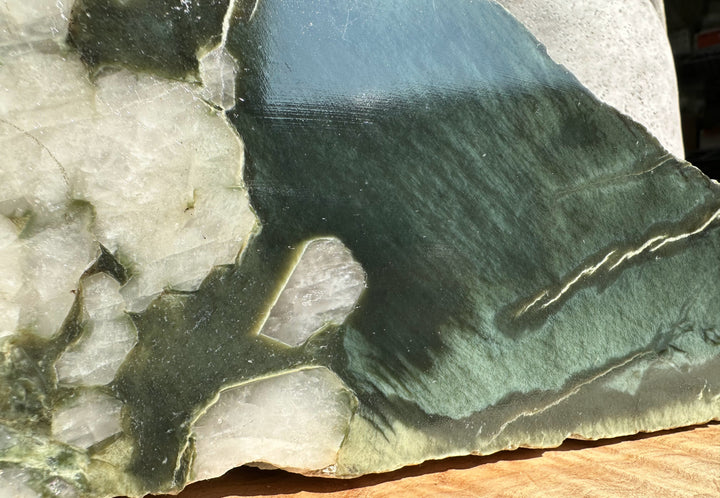 Wyoming Rough Jade with dark green surface surrounded by light gray rock.