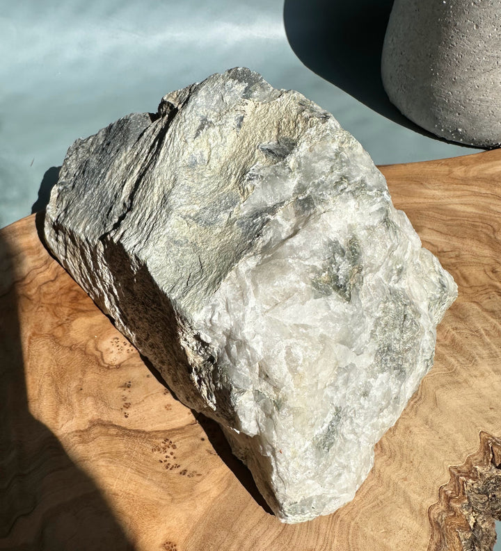 Rough Wyoming jade with a greenish dark interior and light gray outer matrix on a wooden board