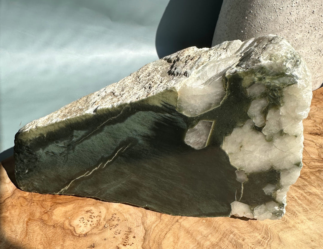 Wyoming jade and quartz fragment showing dark green jade against white crystalline pockets on wood