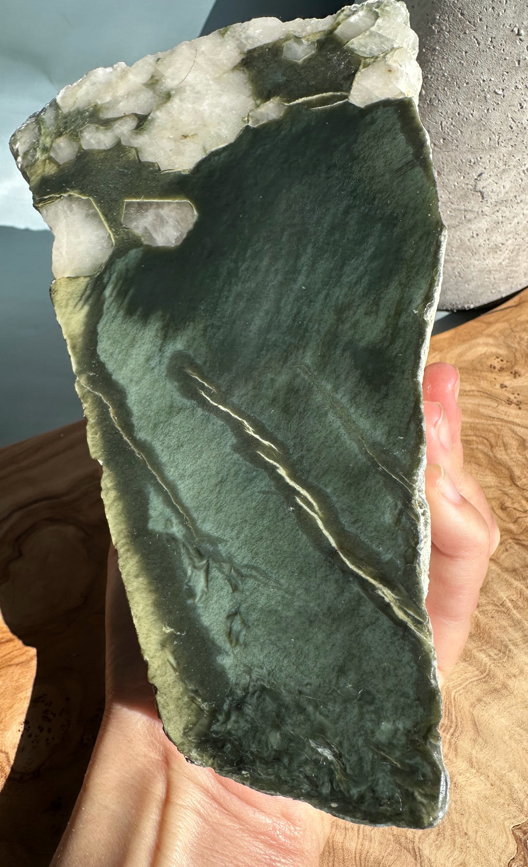 Wyoming Rough Jade block held in hand showing a dark green slab with white crystal edges
