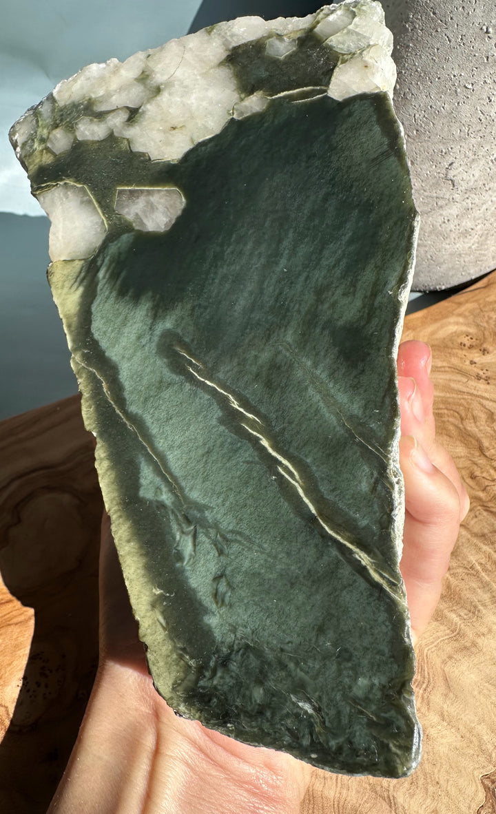 Wyoming Rough Jade block held in hand showing a dark green slab with white crystal edges