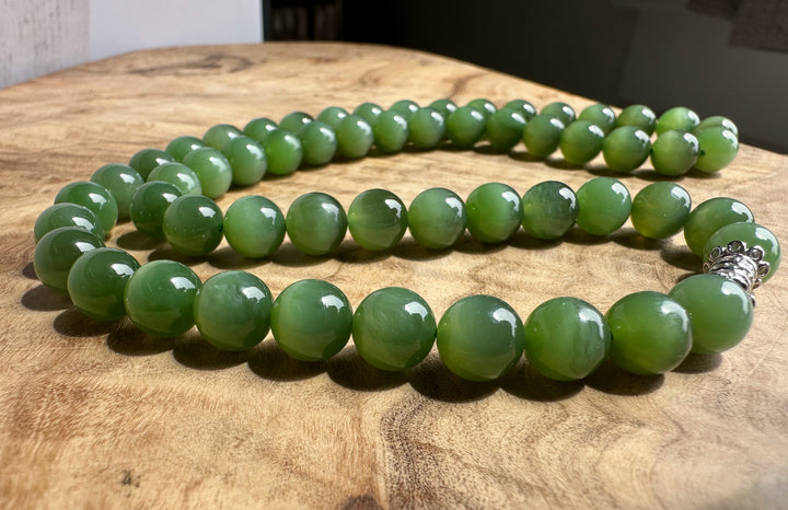 8mm chatoyant Siberian beads in green hues arranged on a wooden surface with a decorative clasp