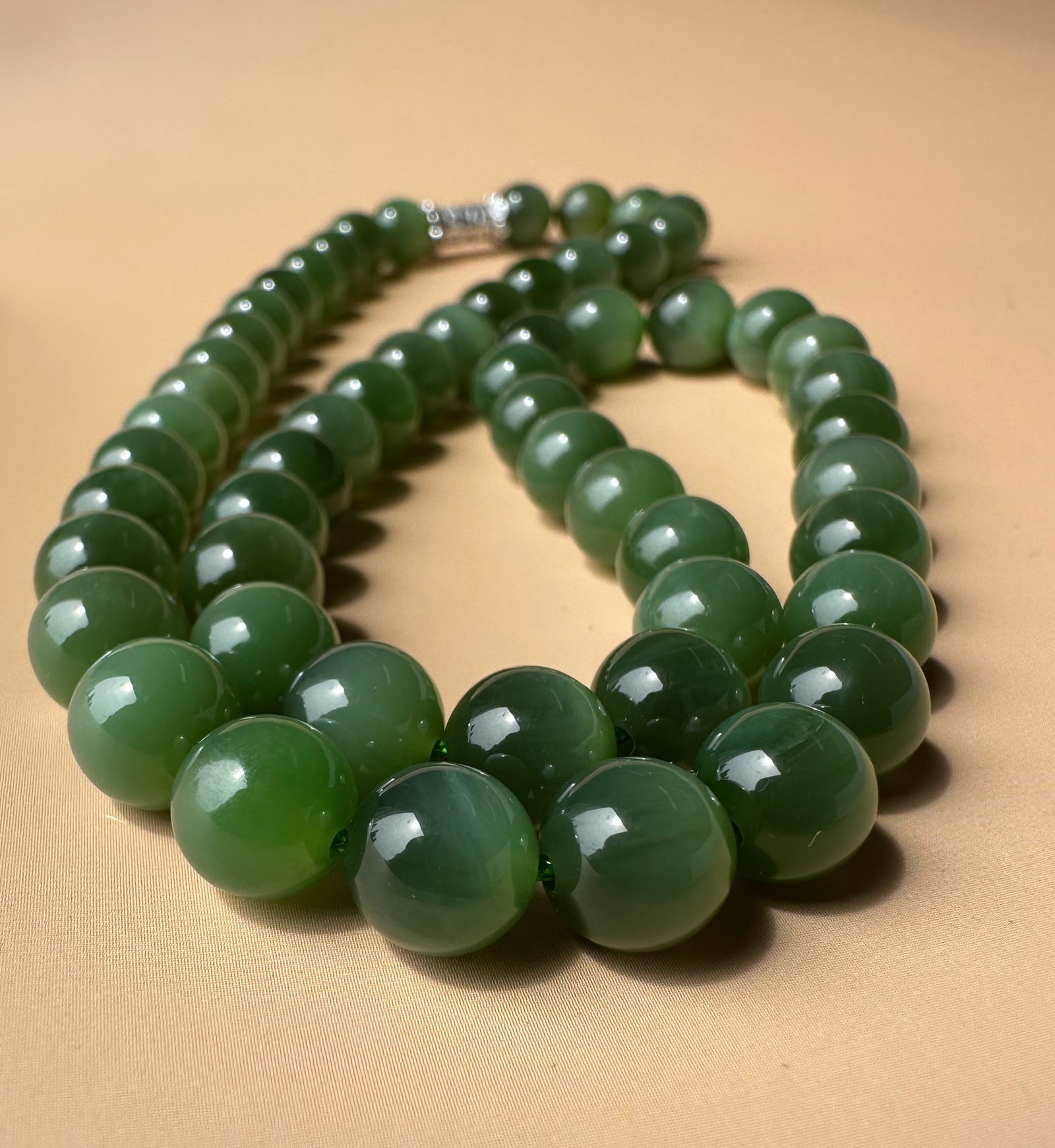 Close up of 8mm chatoyant Siberian beads forming a long strand on a tan background