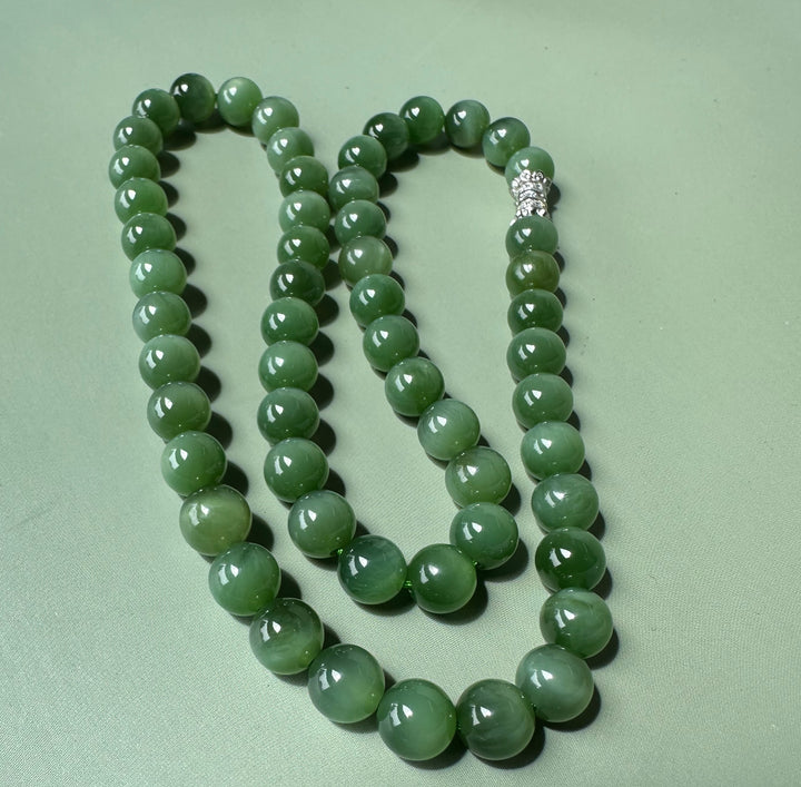 8mm chatoyant Siberian beads arranged in a loose strand on a pale green background