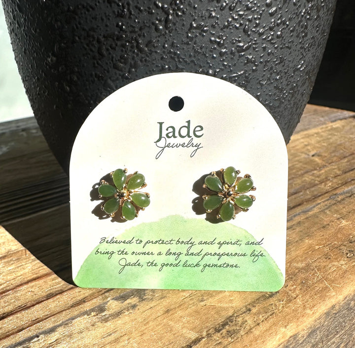 Green jade flower earrings with gold-tone petals on a white display card