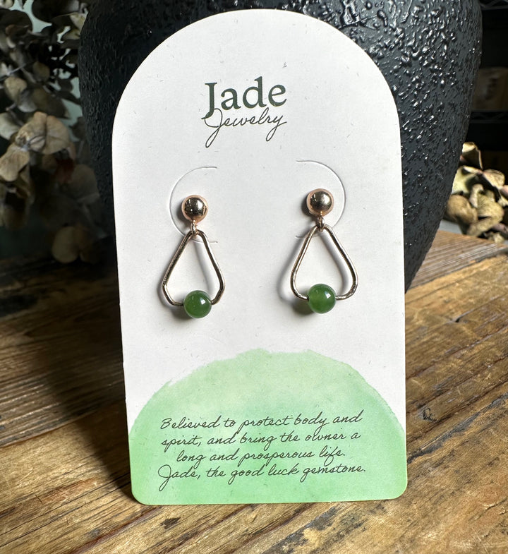 Close-up of Jade Jewelry teardrop earrings with green jade beads on a white display card