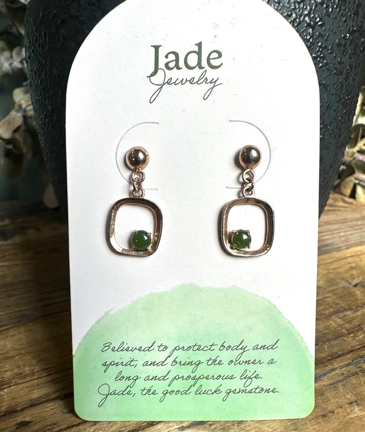 Gold tone drop earrings with square open frames and green beads displayed on a Jade Jewelry card