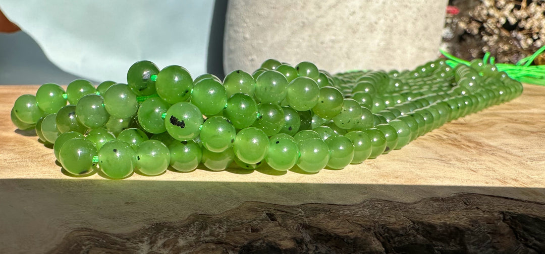 Group of glossy green 6mm beads on a wooden surface showing translucence