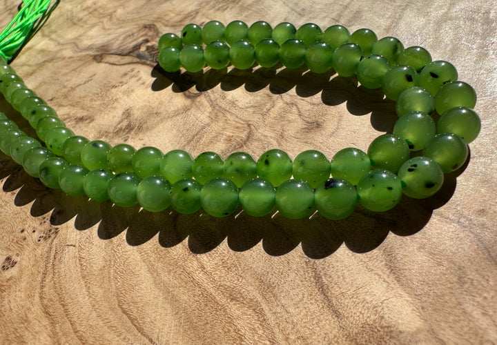 Close up of bright green 6mm round beads on a strand