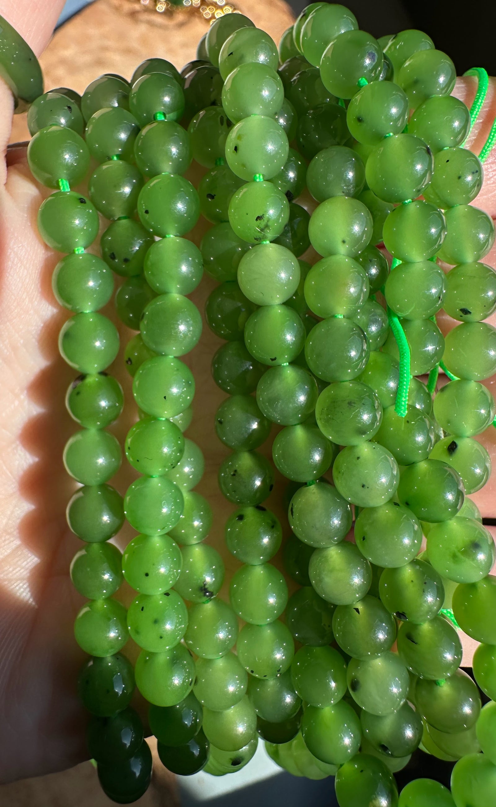 Green 6mm round beads in unstrung strands held in hand