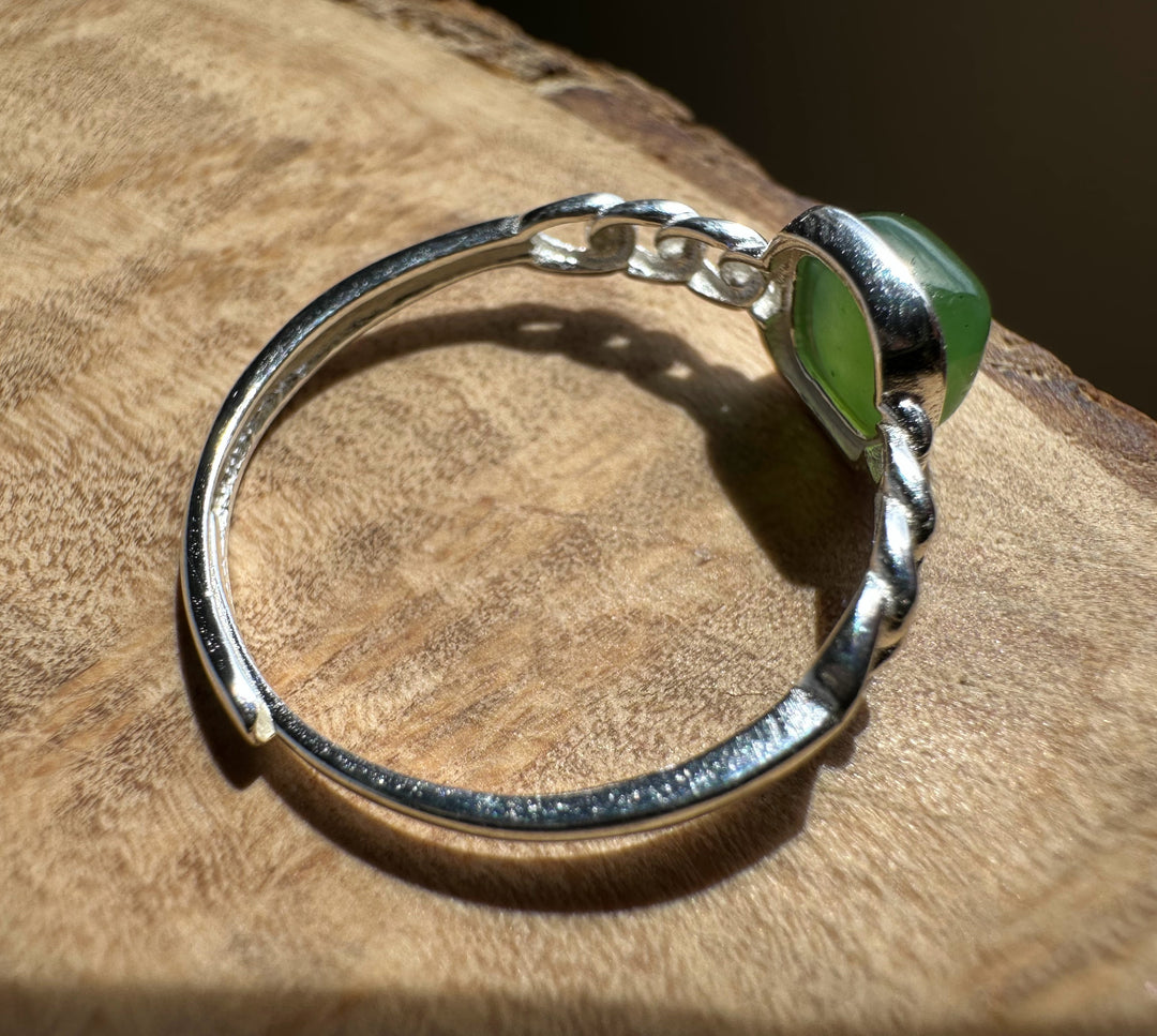 green jade and silver ring on wooden base