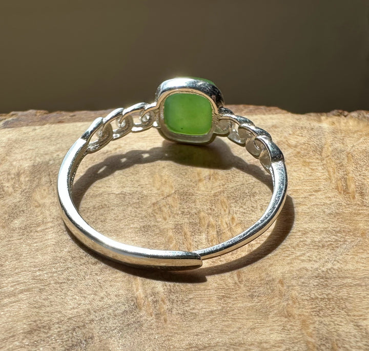 green jade and silver ring on wooden base with light coming through