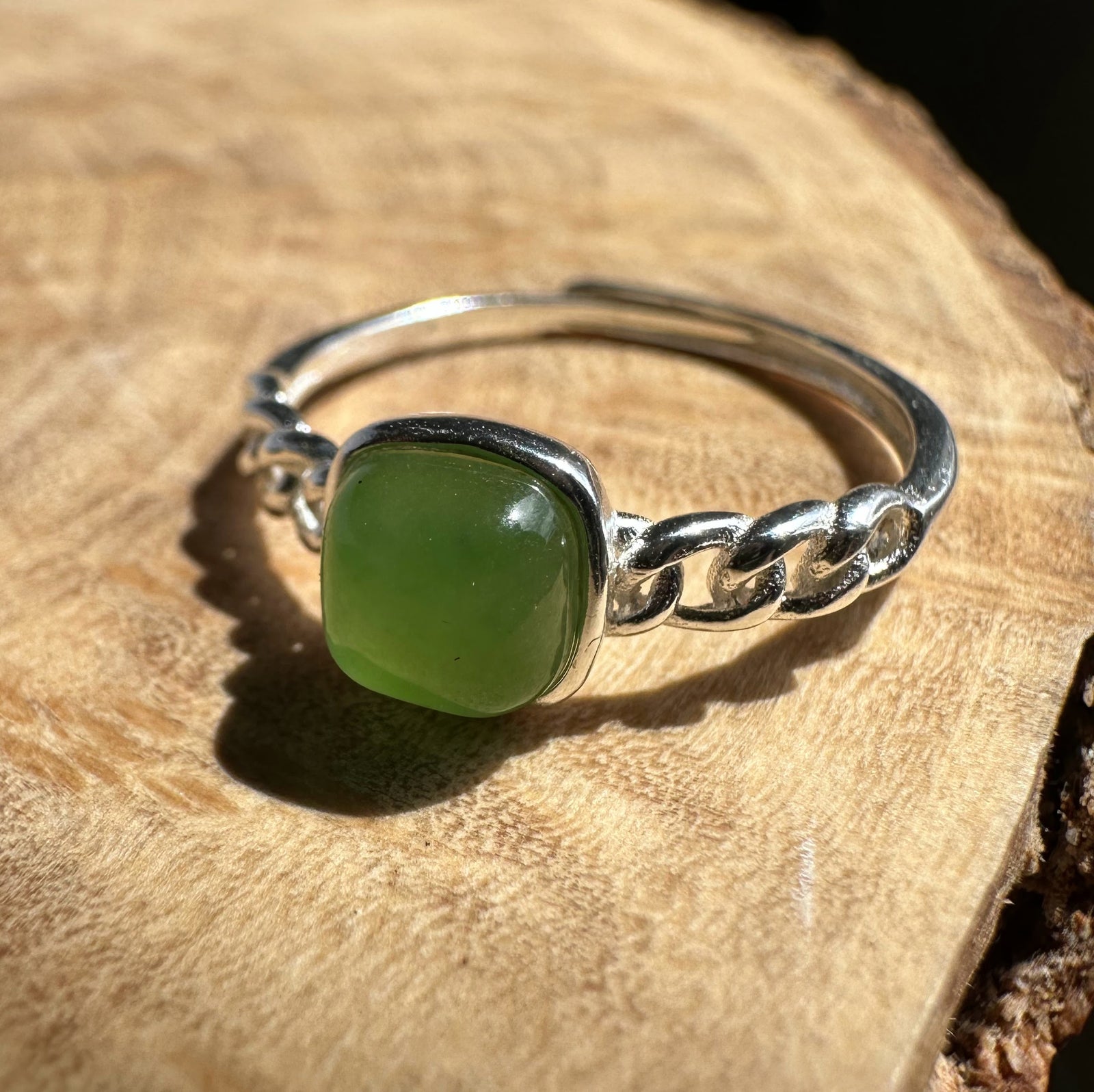 green jade and silver ring on wooden base