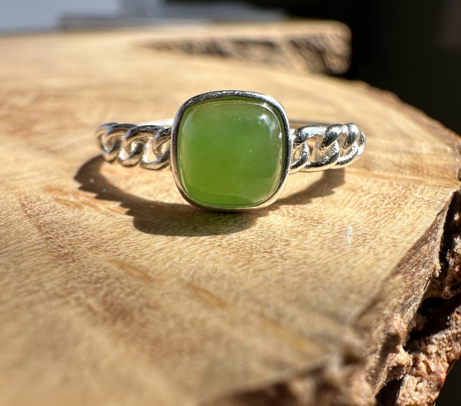 Green jade silver ring on wooden base