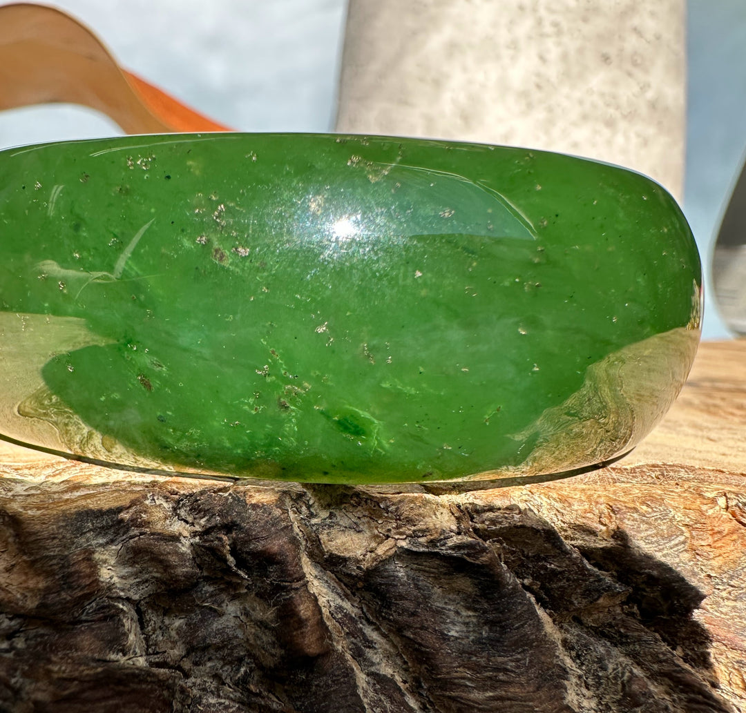 Side view of polished green jade oval bangle 68mm with natural inclusions