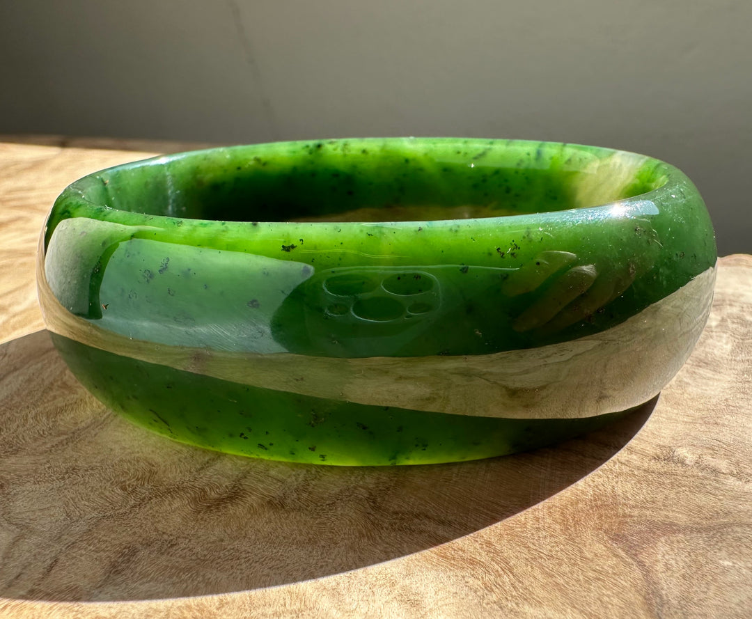 Close up of jade oval bangle 68mm showing bright green nephrite with a polished inner edge.