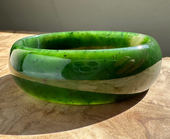 Close up of jade oval bangle 68mm showing bright green nephrite with a polished inner edge.