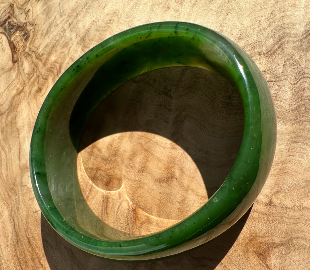 Overhead view of jade oval bangle 68mm with a thick emerald green band and the circular inner opening.