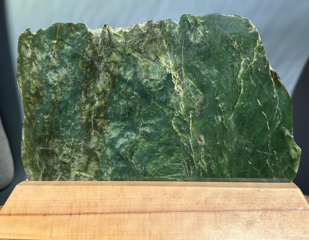 Canadian Jade Slab on a light wooden base with a jagged top edge and green marbling.
