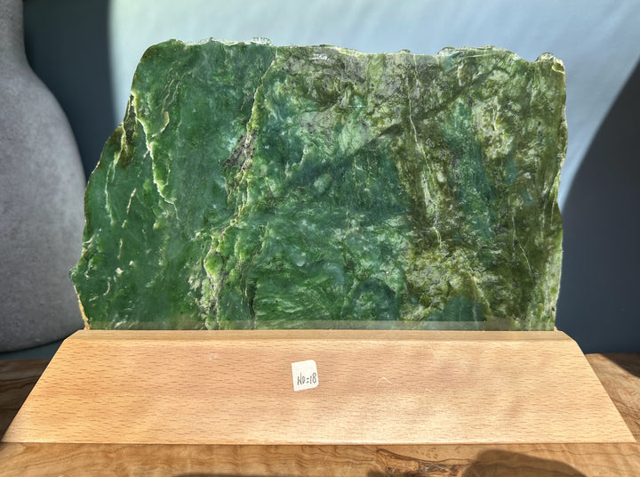 Canadian Jade Slab on a wooden display base with rough edges and rich green color.