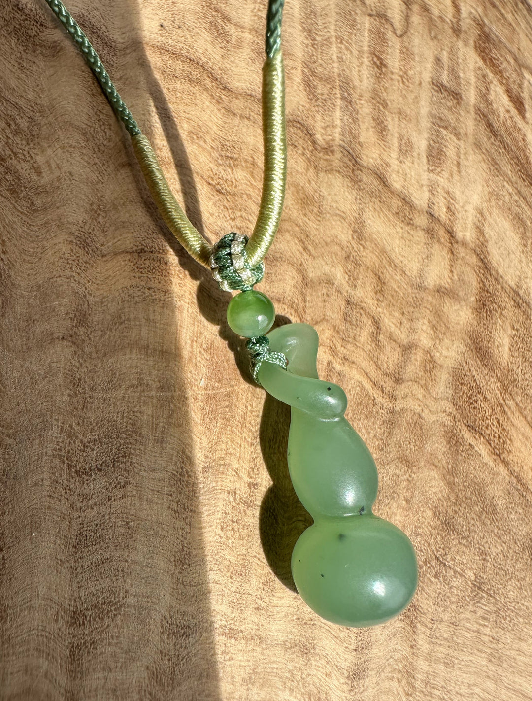 Close-up of knot and green nephrite beads on a two-tone Hulu pendant cord