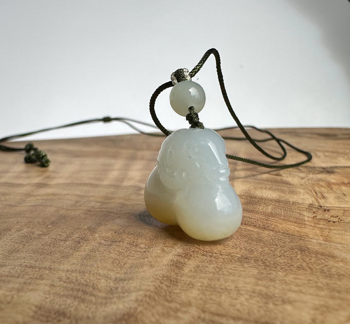 White and brown jade pendant on a wood surface and white backround