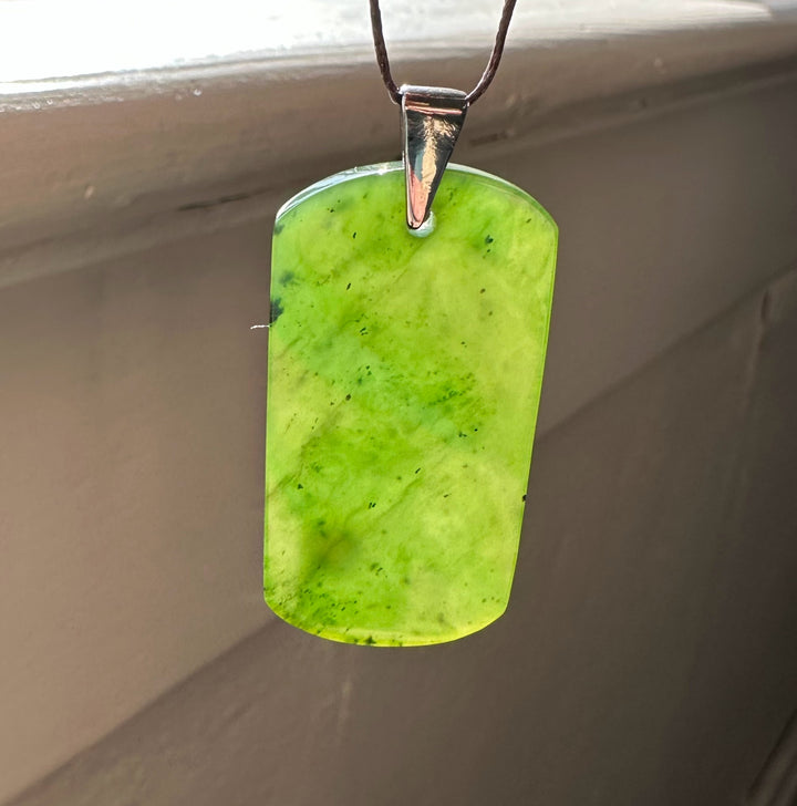 Lime green jade dog tag pendant on a brown cord