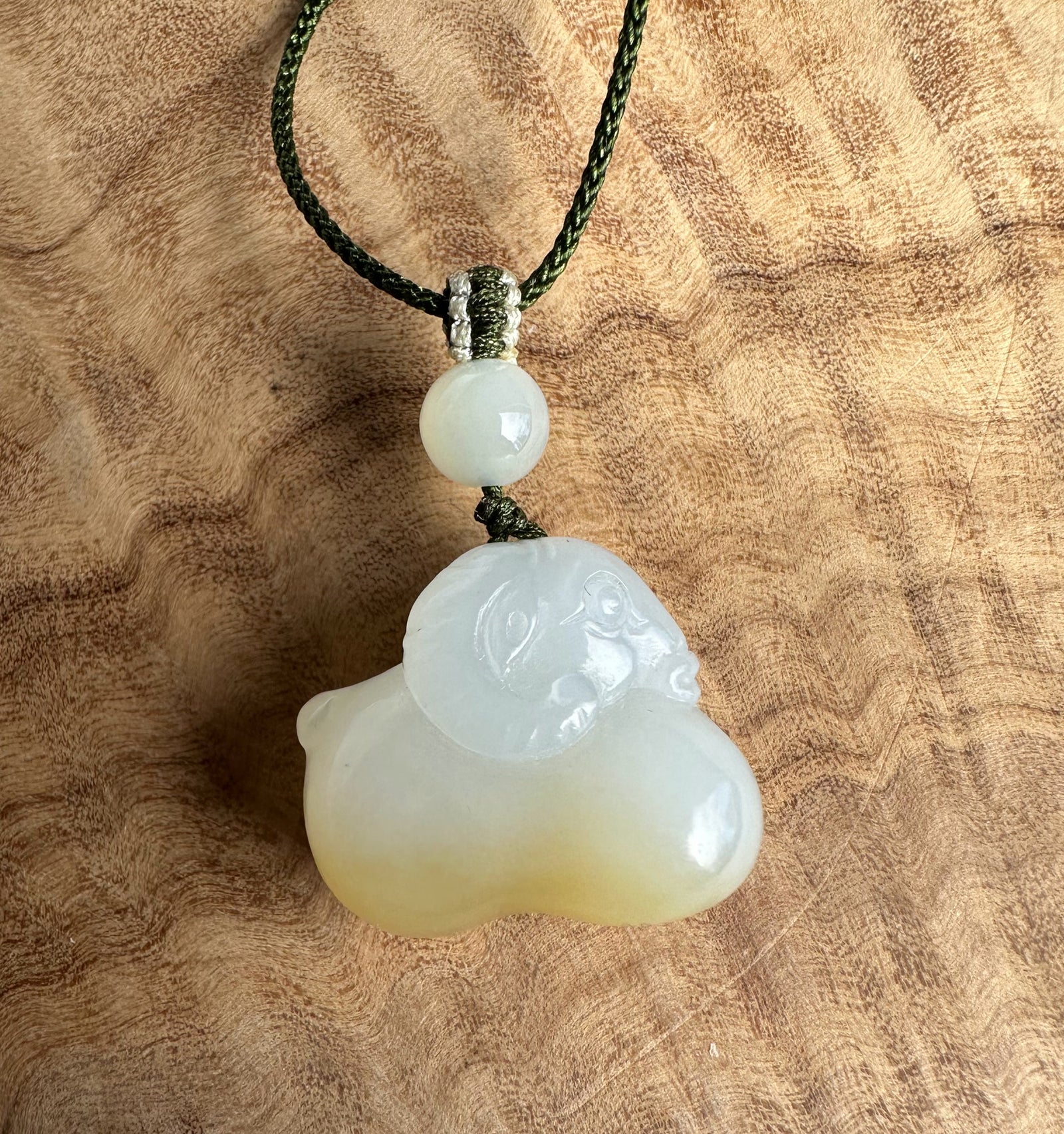 White and brown jade pendant on a wood surface