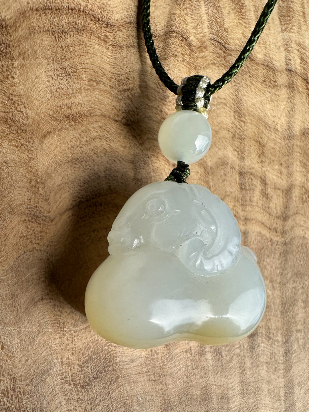 White and brown jade pendant on a wood surface