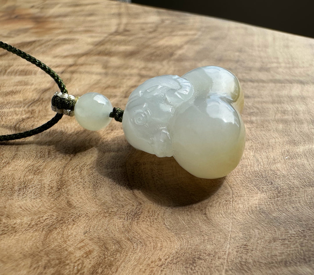 White and brown jade pendant on a wood surface