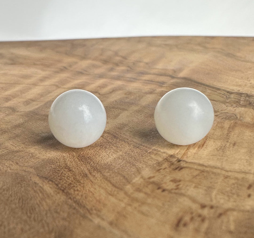 round white jade stud earrings on wood display