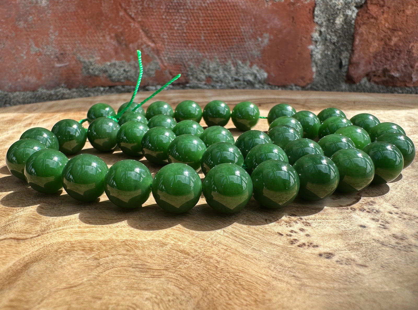 Rich dark green Siberian beads on wooden base and a brick backdrop