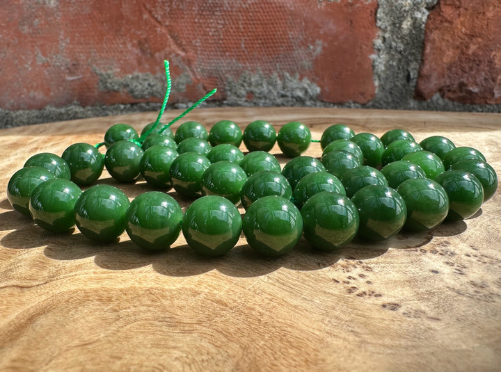 Rich dark green Siberian beads on wooden base and a brick backdrop