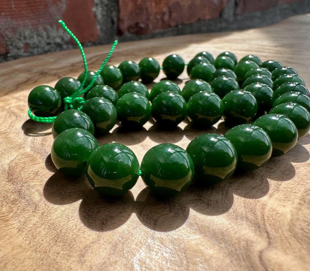 Rich dark green Siberian beads on wooden base and a brick backdrop