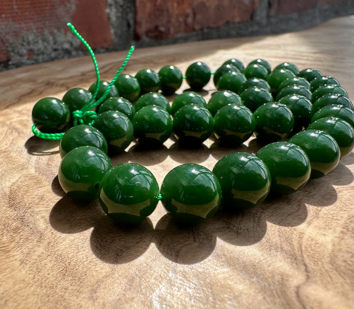 Rich dark green Siberian beads on wooden base and a brick backdrop