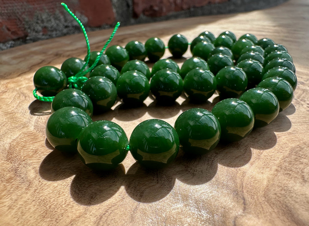 Rich dark green Siberian beads on wooden base and a brick backdrop