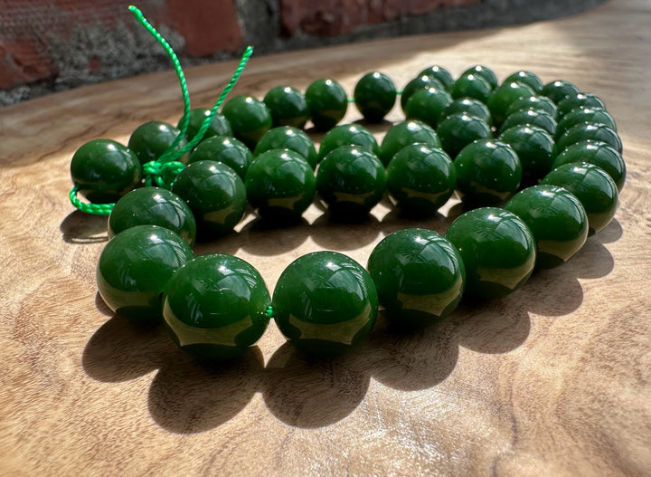Rich dark green Siberian beads on wooden base and a brick backdrop