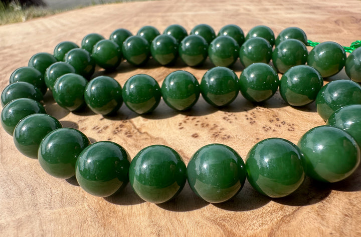 Rich dark green siberian beads on wooden base little bit of grass in the background