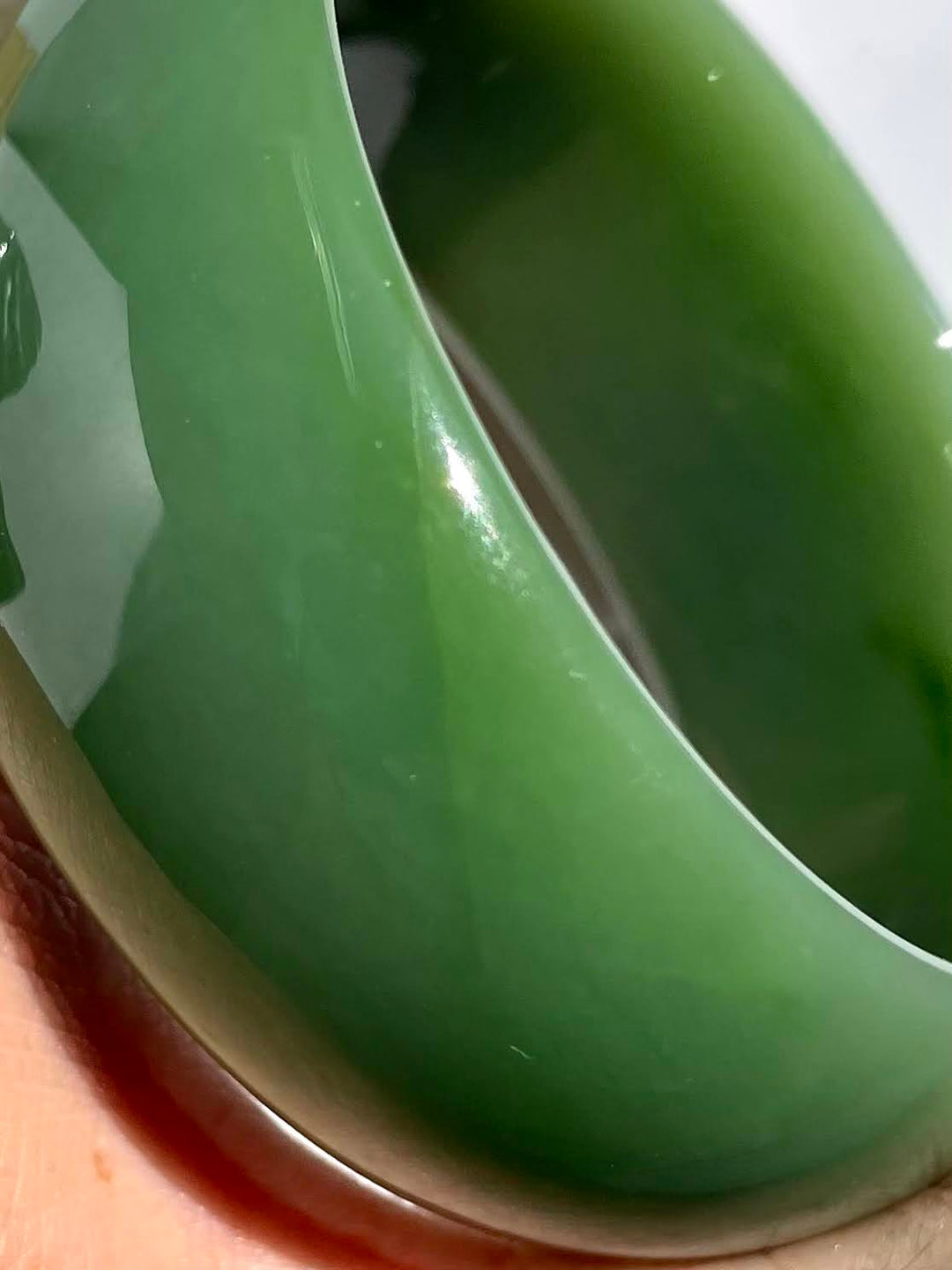 Tilted view of the green jade bangle highlighting its thick rim and smooth interior